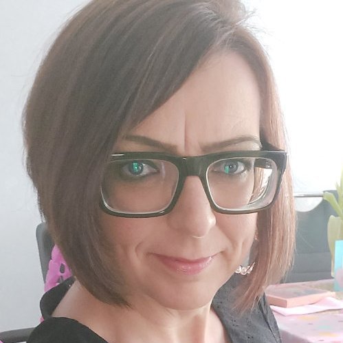 Porträt von Claudia Bartsch mit braunen Haaren, Brille und einem freundlichen Gesichtsausdruck.