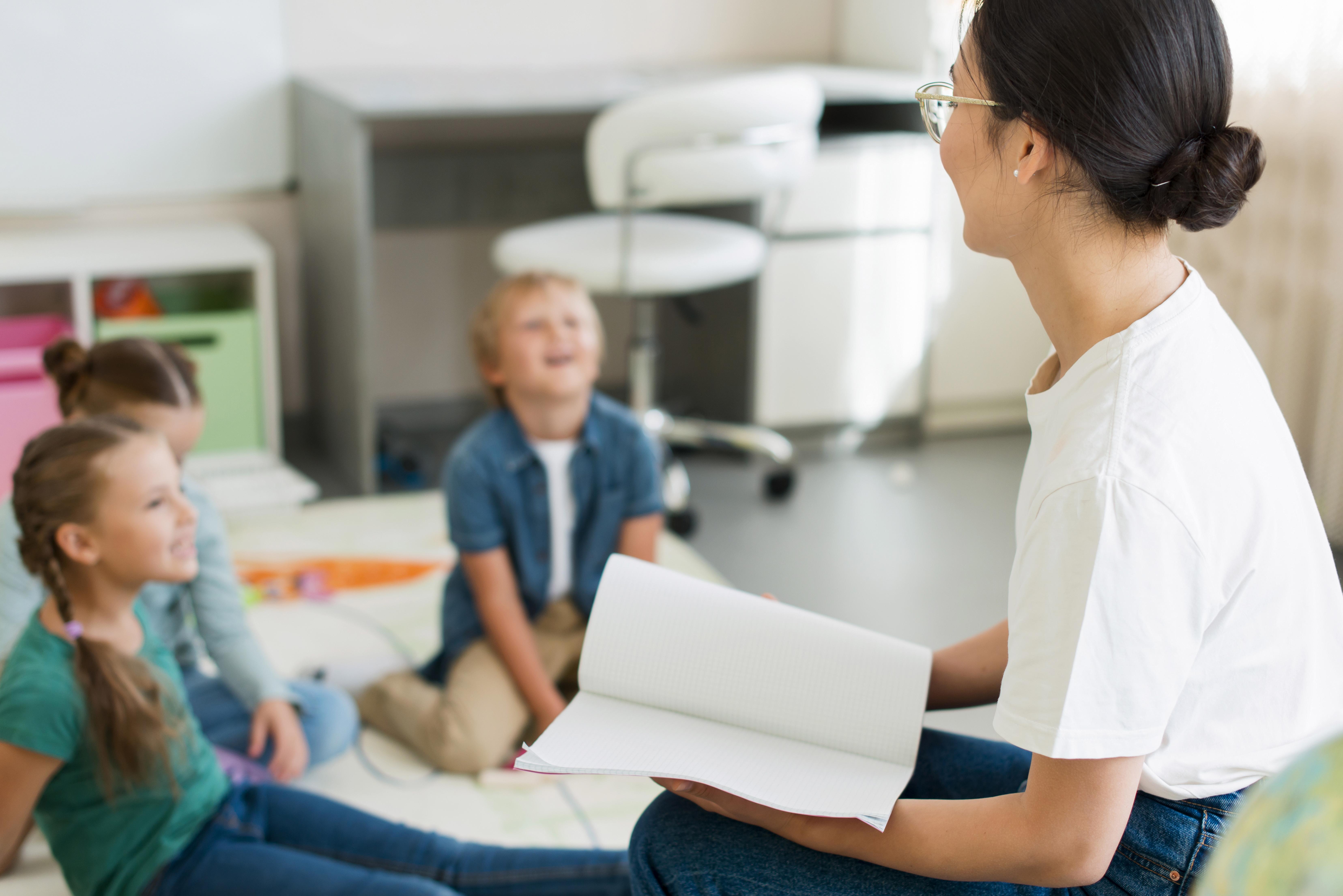 Kinder hören aufmerksam ihrer Lehrerin zu.