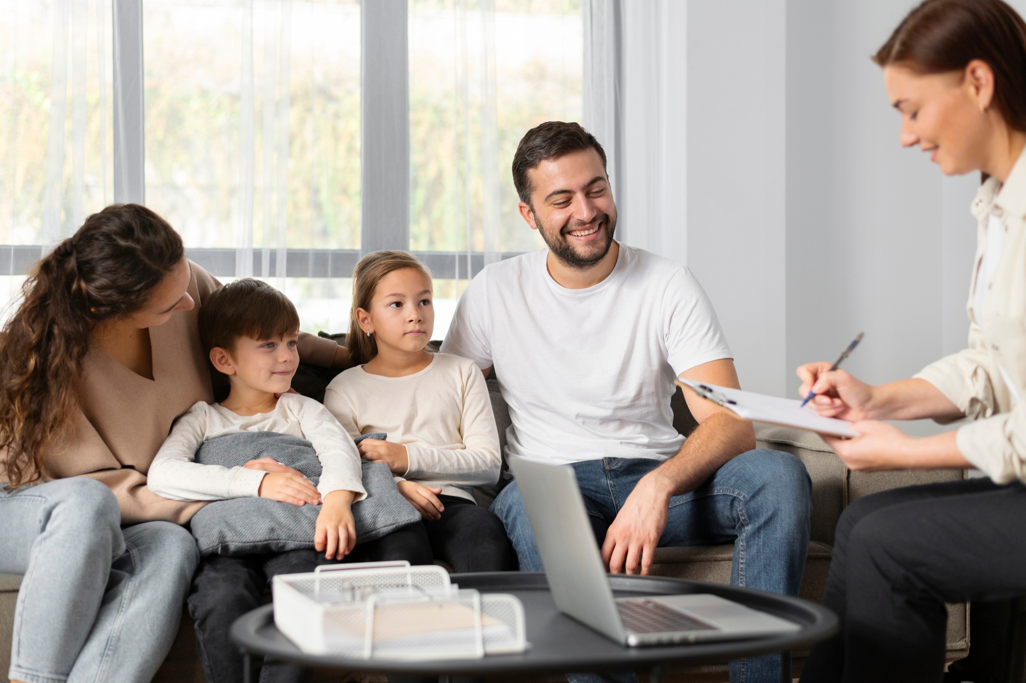 Patchwork-Familie sitzt gemeinsam auf dem Sofa und spricht kit einer Beraterin